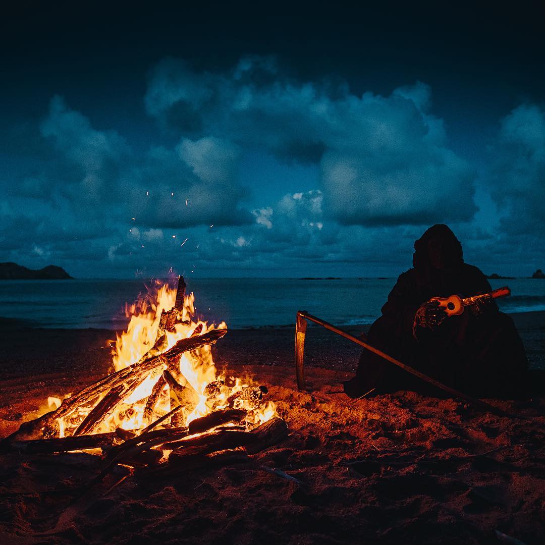 Death plays the ukulele on the beach